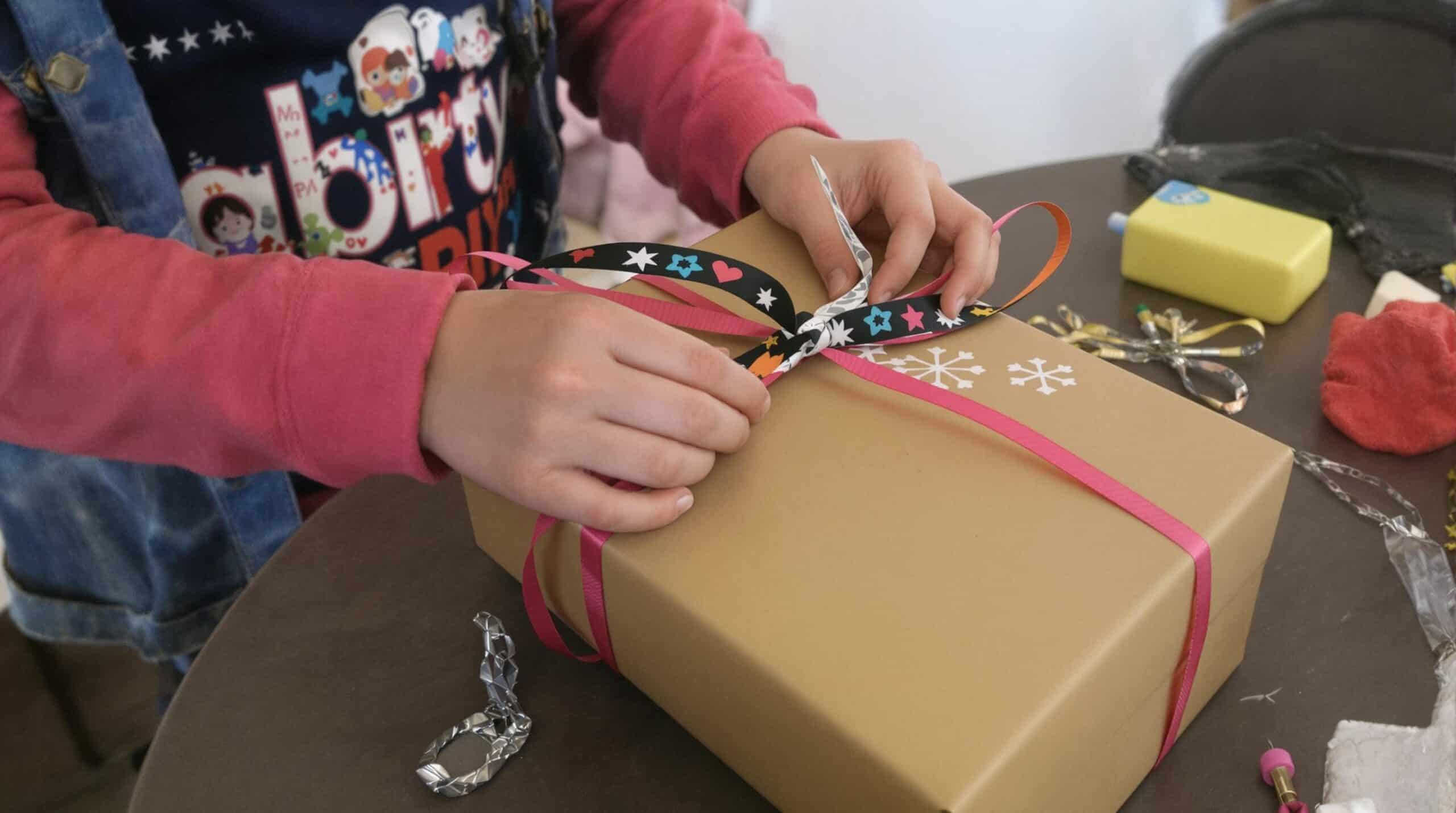 Ein Kind verpackt ein selbstgemachtes Geschenk