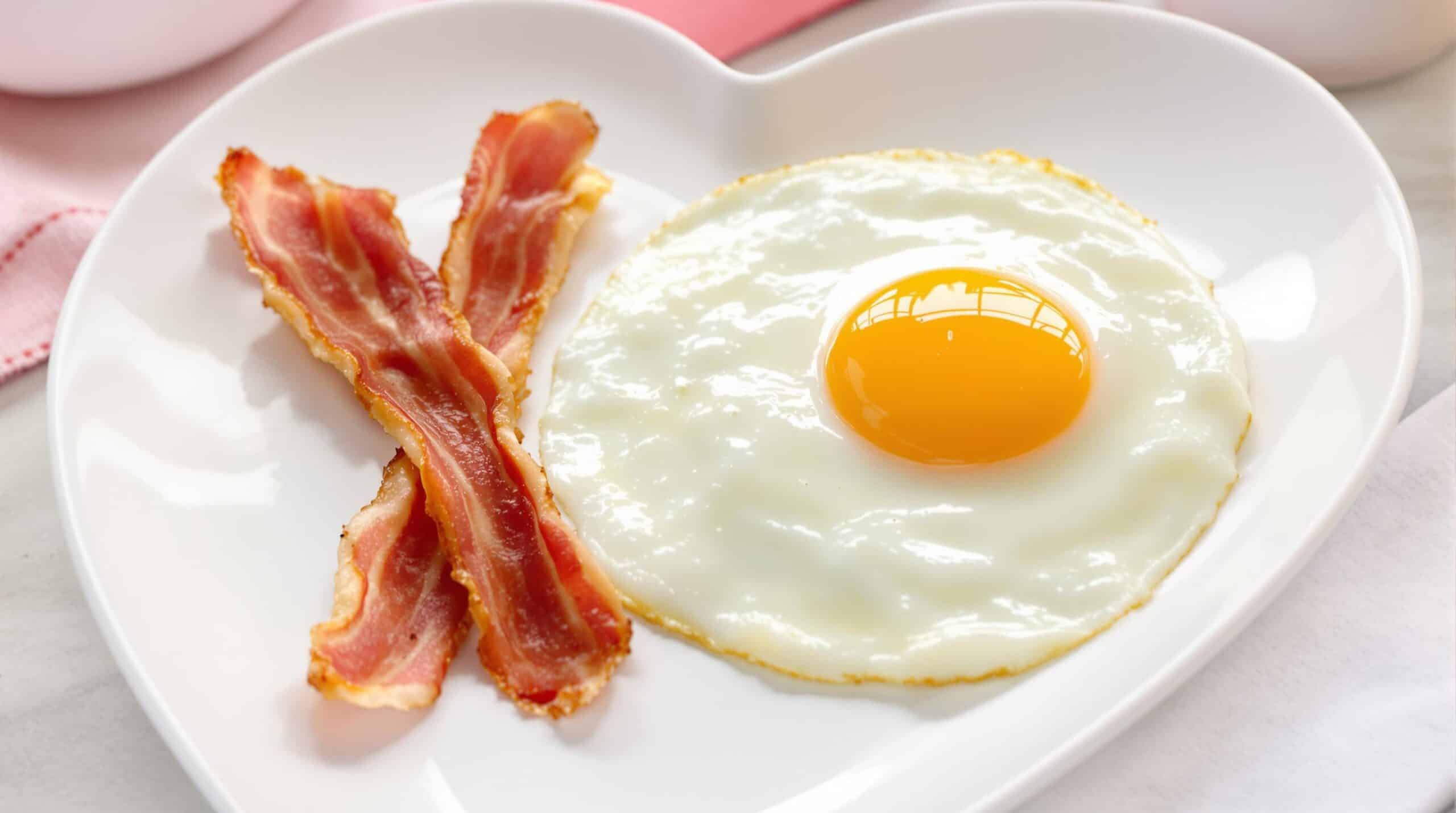 Eier und Speck auf einem herzförmigen Teller