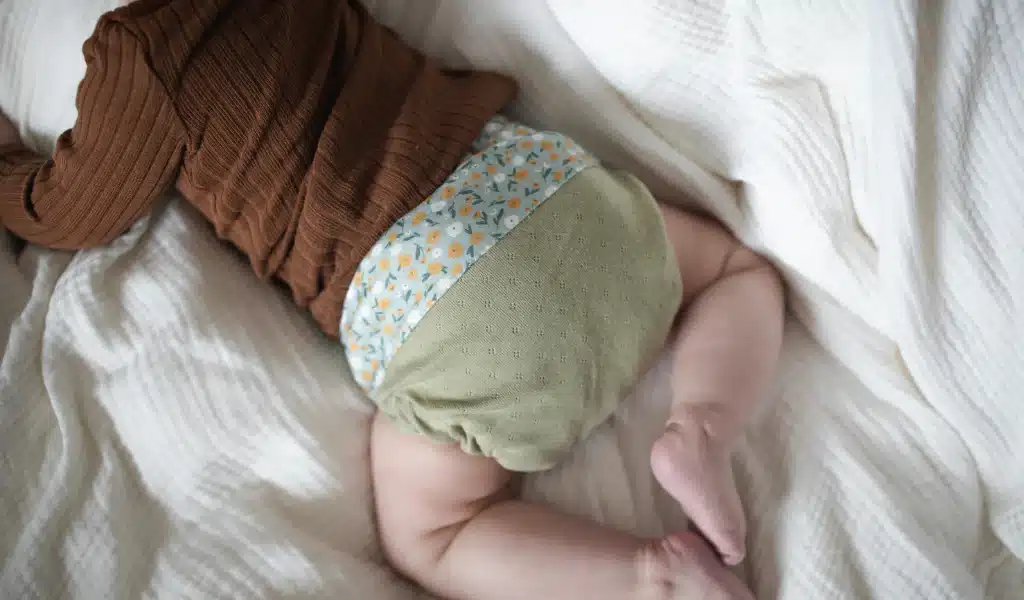 Ein Babykörper von hinten fotografiert mit einer Stoffwindel an.