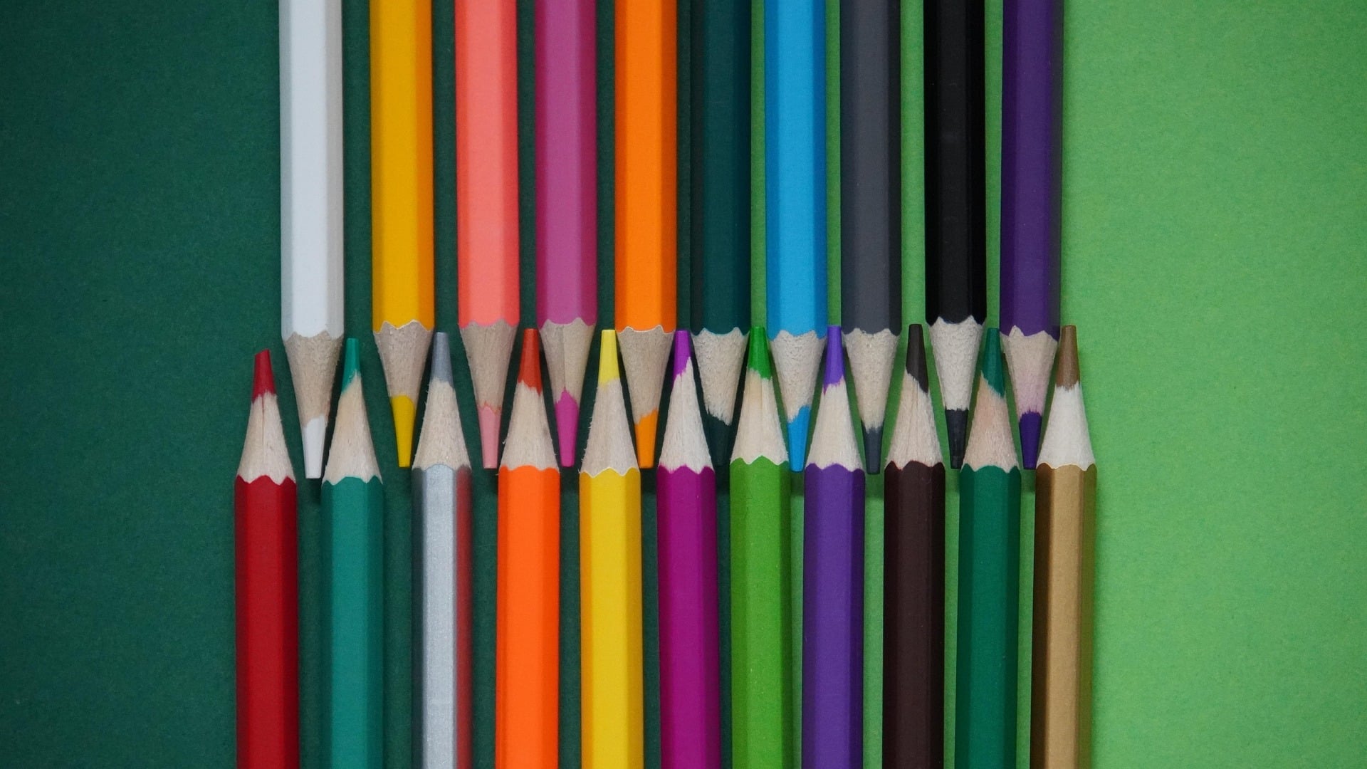 Buntstifte in verschiedenen Farben liegen auf einem einfarbigen Hintergrund